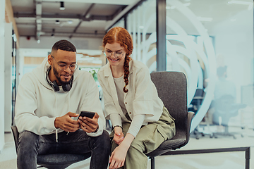 Image showing In a modern office African American young businessman and his businesswoman colleague, with her striking orange hair, engage in collaborative problem-solving sessions