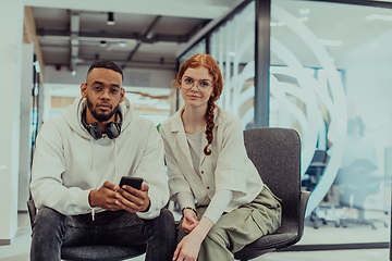 Image showing In a modern office African American young businessman and his businesswoman colleague, with her striking orange hair, engage in collaborative problem-solving sessions