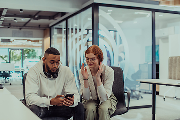 Image showing In a modern office African American young businessman and his businesswoman colleague, with her striking orange hair, engage in collaborative problem-solving sessions