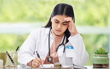 Image showing Stress, anxiety and worry of a busy working woman doctor writing patient, medical and hospital data. Female healthcare professional burnout feeling stressed from a work headache and report deadline