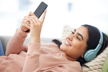 Image showing Phone, music and relaxation with a young woman lying down, resting and streaming songs online. Enjoying free time, relaxing and resting over the weekend at home. Browsing social media on the internet