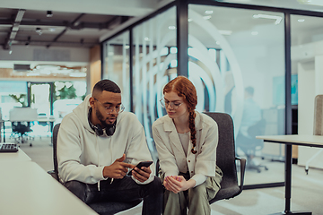 Image showing In a modern office African American young businessman and his businesswoman colleague, with her striking orange hair, engage in collaborative problem-solving sessions