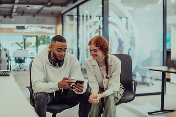 Image showing In a modern office African American young businessman and his businesswoman colleague, with her striking orange hair, engage in collaborative problem-solving sessions