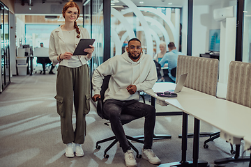 Image showing In a modern office African American young businessman and his businesswoman colleague, with her striking orange hair, engage in collaborative problem-solving sessions