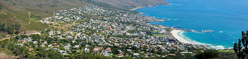 Image showing Panoramic landscape of a large city on the coast from above. Beautiful scenic and aerial view of a popular tourist town or residential area with greenery and the ocean in nature during summer