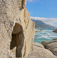 Image showing Landscape of rocks and the ocean in Camps Bay, Cape Town, South Africa. Scenic view of big rocks on the shoreline of the beach in summer. Large stones in the sea at famous tourist destination
