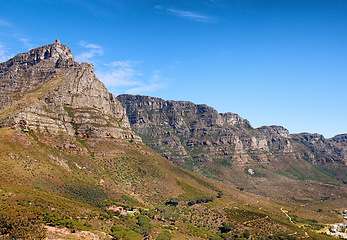 Image showing Landscape of mountains on a blue sky background with copy space. Beautiful view of mountain outcrops with hills covered in green grass, trees and bushes on a popular landmark location in South Africa