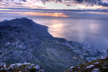 Image showing Beautiful landscape of an iconic landmark and famous travel or vacation destination in South Africa at sunset. Aerial view of the sea, Table Mountain and a city on a cloudy evening with copy space