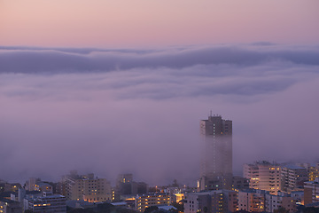 Image showing Panoramic view of clouds covering buildings at sunset in the popular city of Cape Town, South Africa with copy space. A peaceful, misty sunrise over signal hill. Landscape of a modern town at night