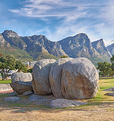 Image showing Landscape view of mountains beach rocks in famous travel or tourism destination with lush trees and grass. Scenic Twelve Apostles with blue sky and clouds in Camps Bay, Cape Town, South Africa