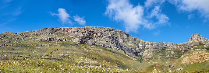 Image showing Widescreen landscape view of Table Mountain in Cape Town, South Africa. Low panoramic scenery of a popular natural landmark and tourist attraction during the day against a blue cloudy sky in summer