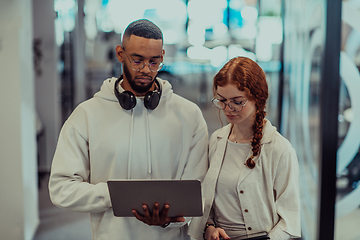 Image showing In a modern office African American young businessman and his businesswoman colleague, with her striking orange hair, engage in collaborative problem-solving sessions