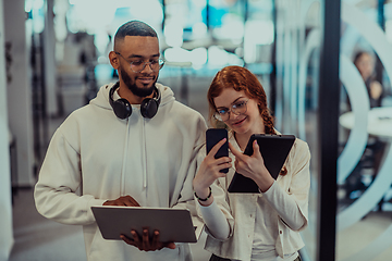 Image showing In a modern office African American young businessman and his businesswoman colleague, with her striking orange hair, engage in collaborative problem-solving sessions