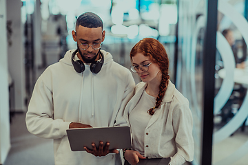 Image showing In a modern office African American young businessman and his businesswoman colleague, with her striking orange hair, engage in collaborative problem-solving sessions