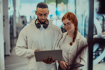 Image showing In a modern office African American young businessman and his businesswoman colleague, with her striking orange hair, engage in collaborative problem-solving sessions