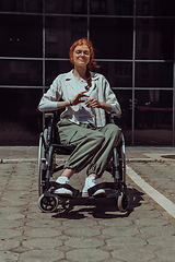 Image showing In front of a modern corporate building, a young woman sitting in a wheelchair confidently, symbolizing empowerment, inclusivity, and the strength to overcome challenges in the business world