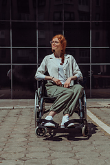 Image showing In front of a modern corporate building, a young woman sitting in a wheelchair confidently, symbolizing empowerment, inclusivity, and the strength to overcome challenges in the business world