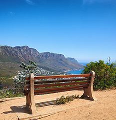 Image showing Bench with a beautiful view of the mountain and sea against a clear blue sky background with copy space. Relaxing spot for a peaceful break to enjoy the scenic landscape after a hike up a cliff