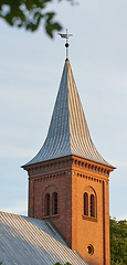 Image showing Tall infrastructure and tower used to symbolize faith and Christian or Catholic devotion. Architecture roof design of church steeple and spire on gothic style cathedral building against blue sky.