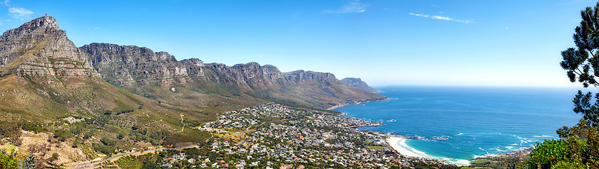 Image showing Beautiful coastal landscape with mountains surrounded an urban city in a popular tourism destination. Aerial view of Cape Town city with Mountain outcrops and the ocean on a blue sky with copy space