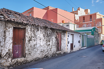 Image showing Exterior of decaying brick buildings with peeling paint in a street of Santa Cruz de La Palma. Architectural details of an abandoned rustic property with damaged and aged doors or entrances outside