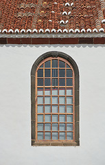 Image showing Architecture of a grey wall with an arched window outside. Exterior texture details of an old rustic residential building or church with vintage wooden windows discovered in Santa Cruz de La Palma