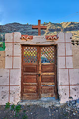 Image showing Old abandoned church or cathedral with a weathered wall and broken wooden door. Vintage and aged religious building built in a traditional architectural style or design with a crucifix for faith