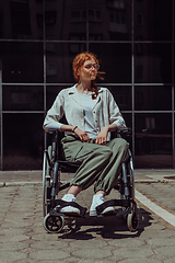 Image showing In front of a modern corporate building, a young woman sitting in a wheelchair confidently, symbolizing empowerment, inclusivity, and the strength to overcome challenges in the business world