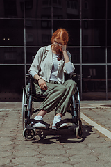 Image showing In front of a modern corporate building, a young woman sitting in a wheelchair confidently, symbolizing empowerment, inclusivity, and the strength to overcome challenges in the business world