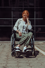 Image showing In front of a modern corporate building, a young woman sitting in a wheelchair confidently, symbolizing empowerment, inclusivity, and the strength to overcome challenges in the business world