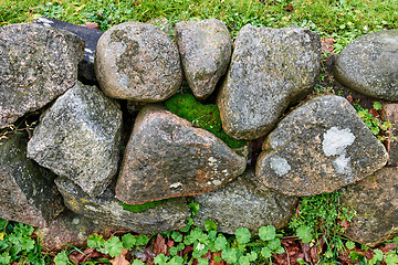 Image showing Background. Nature background of a rock garden wall outside on a sunny day with delicate moss and plants growing between the stones. Wallpaper of structural support barrier fencing in a garden.