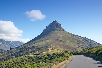 Image showing A road leading to Lions Head in Cape Town, South Africa against blue sky copyspace on a sunny morning. A highway along a peaceful mountain landscape with scenic views or lush green bushes and trees