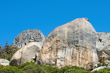 Image showing Rocks and boulders on a mountain peak with green lush bush growing on Lions Head in Cape Town with sky and copyspace. Large area of wilderness landscape with calm fresh air and harmony in nature