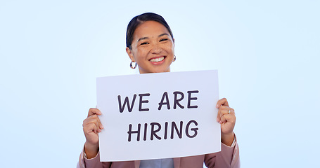Image showing Recruitment, smile and portrait of woman in a studio with a hiring sign, poster or board for job. Happy, employment and face of young Asian female person advertising a career offer by blue background