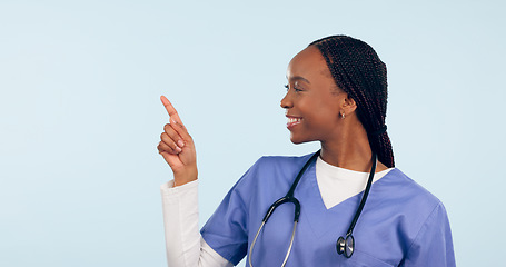 Image showing Smile, information and a nurse black woman pointing to space in studio on a blue background for healthcare. Medical, presentation and checklist with a happy young medicine professional showing mockup