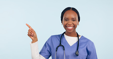 Image showing Portrait, information and a nurse black woman pointing to space in studio on a blue background for healthcare. Smile, medical and checklist with a happy young medicine professional showing mockup