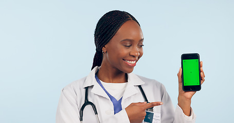 Image showing Green screen, doctor pointing and black woman with phone for telehealth, wellness app and medical news. Healthcare, mockup and person on smartphone for clinic website, promotion and contact in studio