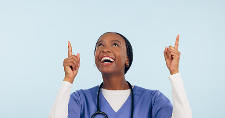Image showing Smile, announcement and a nurse black woman pointing to space in studio on a blue background for healthcare. Medical, presentation and info with a happy young medicine professional showing mockup