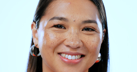 Image showing Happy, smile and portrait of Asian woman in a studio with positive, good and confident attitude. Excited, headshot and closeup face of young female person with happiness isolated by blue background.