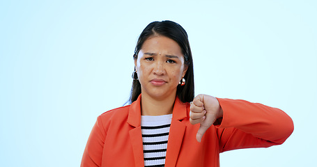 Image showing Portrait, woman and thumbs down with rejection, no and feedback on a blue studio background. Face, girl and model with facial expression, hand gesture and review with complaint, opinion and decision