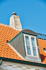 Image showing Chimney chute, window and sunroof skylight designed on house building outside against blue sky background. Construction of exterior architecture on rooftop for fireplace escape and natural sunlight