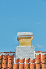 Image showing Brick chimney designed on slate roof of house building outside against blue sky background. Construction of exterior architecture of escape chute built on rooftop for fireplace smoke and heat