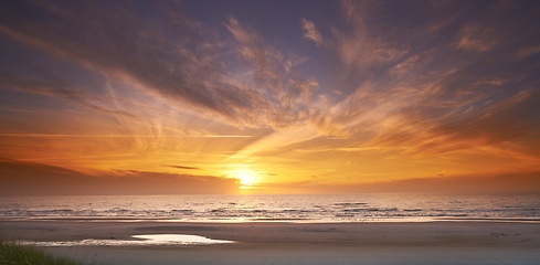 Image showing Seascape and landscape of a golden sunset on the west coast of Jutland in Loekken, Denmark. Beautiful cloudscape on an empty beach at dusk. Clouds over the ocean and sea in the evening with copyspace