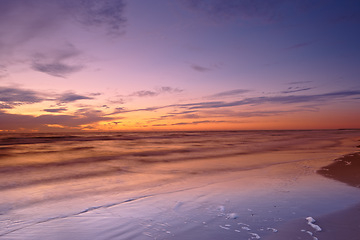 Image showing Seascape and landscape of a beautiful sunset on the west coast of Jutland in Loekken, Denmark. Sun setting on the horizon on an empty beach at dusk over the ocean and sea in the evening