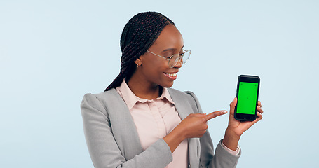 Image showing Black woman, pointing at smartphone and green screen, advertising mockup with tracking marker in studio. Information, marketing for app or website, communication and ads for tech on blue background