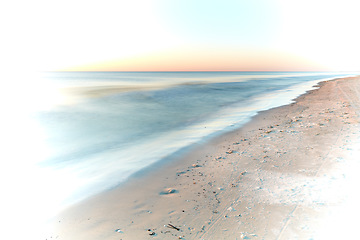 Image showing Long exposure of waves washing on empty beach with copyspace at sunset with creative white vignette. Beautiful seascape and landscape at dusk on west coast of Jutland, Loekken, Denmark. Ocean and sea