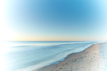 Image showing Copyspace seascape and landscape of a pretty sunset on the westcoast of Jutland in Loekken, Denmark. Beautiful view on an empty beach at dusk. Sun rising over the ocean and sea in the morning