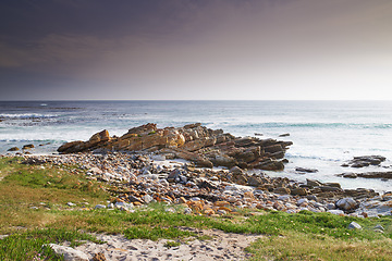 Image showing A rocky coastline in the Western Cape, South Africa on a hot summer day. Clear skies and beaches, a perfect getaway filled with self care resorts and wellness outdoor activities with tropical weather