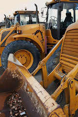 Image showing Bulldozer in action at construction site. An industrial excavator on an open road section loading heavy concrete, rocks and dirt. Motorized machine equipped for pushing material, soil, sand or rubble