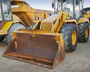 Image showing Bulldozers at a construction site parked after operating. Huge orange powerful building vehicle with a hydraulic piston scoop and black wheels. Heavy machinery outside in an empty space